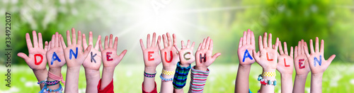 Kids Hands Holding Colorful German Word Danke Euch Allen Means Thank You All. Sunny Green Grass Meadow As Background