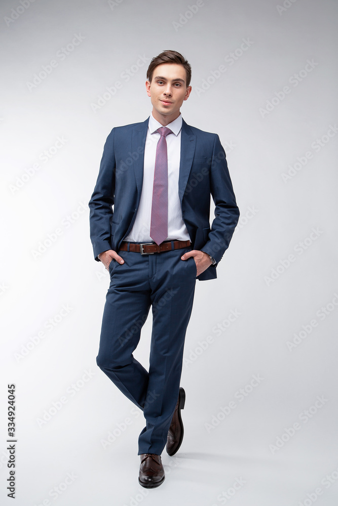 Young, handsome man in a blue suit in a white shirt with a tie on a white background in studio Young, handsome man in a blue suit in a white shirt with a tie on a white background in studio