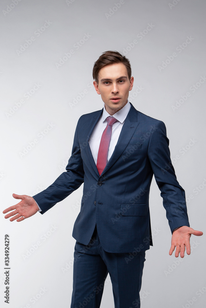 Young, handsome man in a blue suit in a white shirt with a tie on a white background in studio Young, handsome man in a blue suit in a white shirt with a tie on a white background in studio