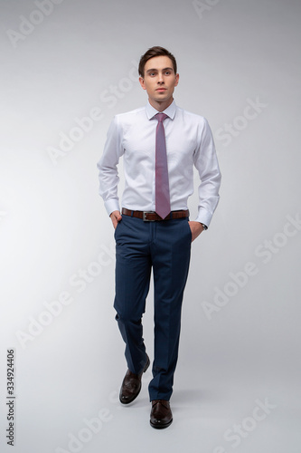 Young, handsome man in a blue suit in a white shirt with a tie on a white background in studio © Viktoria