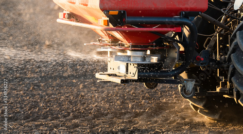 Foto Tractor spreading artificial fertilizers in field
