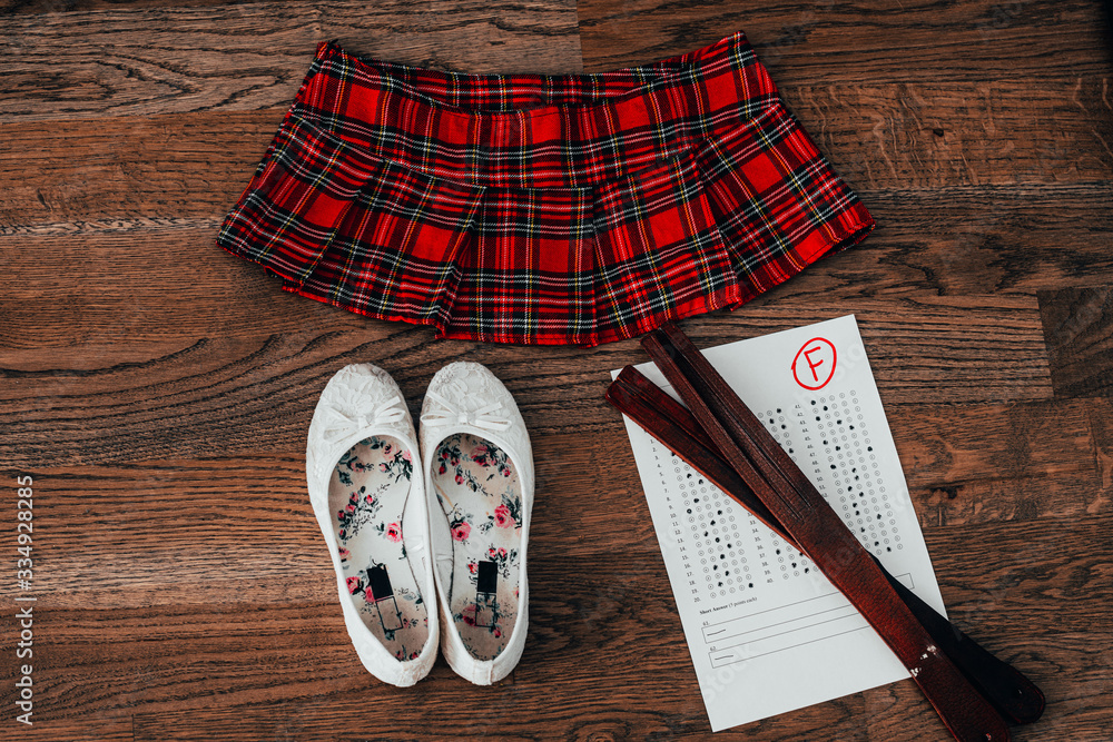 Leather tawse for spanking and report card with "F" mark. Domestic discipline and corporal