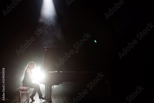 Young musician playing the grand piano on the stage