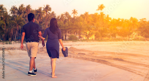 Rich asiatic couple enjoying beautiful sunset walk on the beach