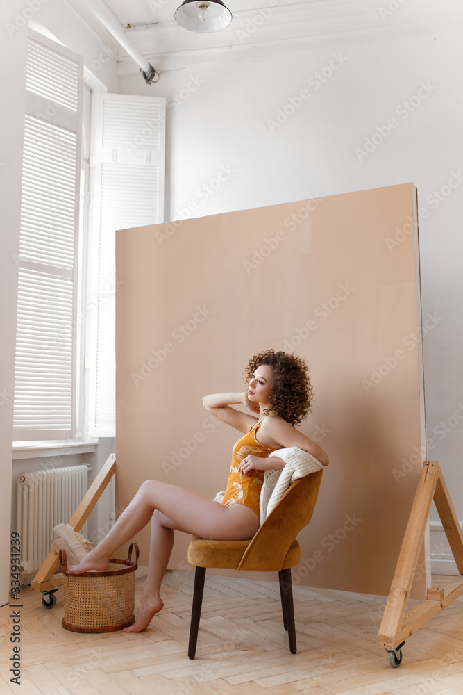 Fun funny playful attractive cheerful girl with afrocudry in a bright yellow bodysuit and sweater laughing posing for the camera enjoying herself on a beige background, fashion shooting Fun funny playful attractive cheerful girl with afrocudry in a bright yellow bodysuit and sweater laughing posing for the camera enjoying herself on a beige background, fashion shooting
