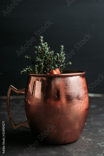 Red oranges cocktail in copper mug (variation of Moscow mule) on the wooden background. Selective focus. Shallow depth of field. photo