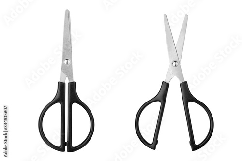 Two silver metal open and closed scissors with black plastic handles on white background isolated close up, steel cutting tool for paper, fabric clippers, haircut shears, tailor pair of scissors