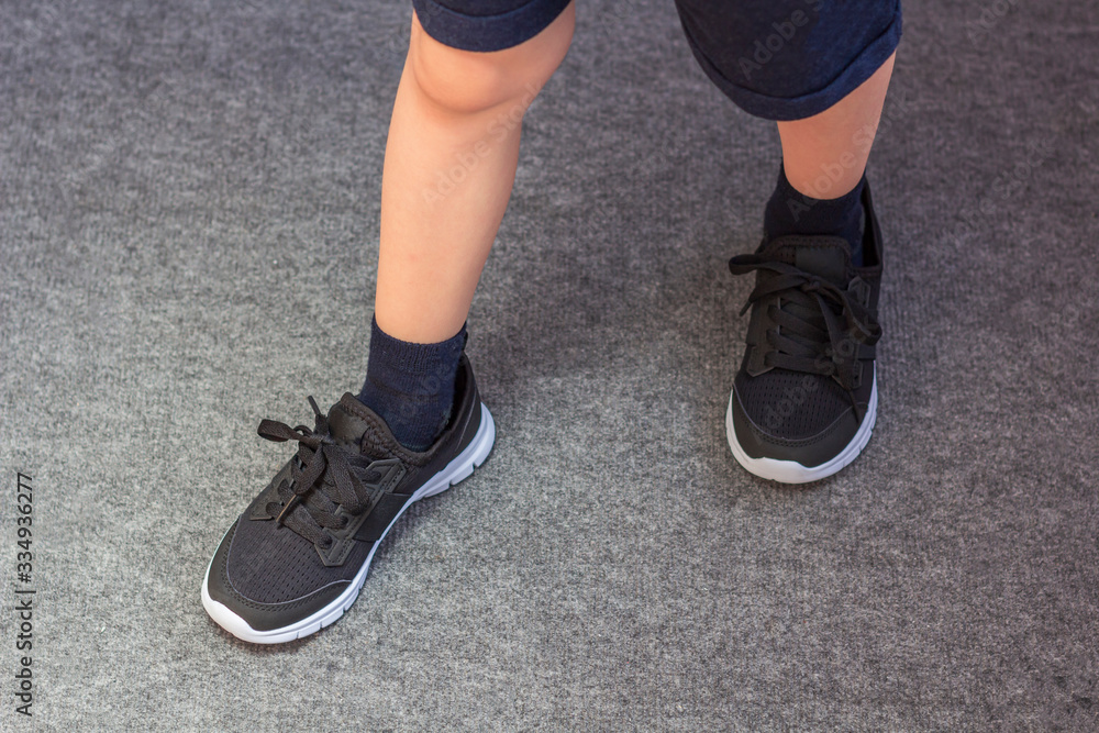 Young boy's legs in textile fashion black sneakers. Children's trendy casual outfit and street fashion. Top view, Close up