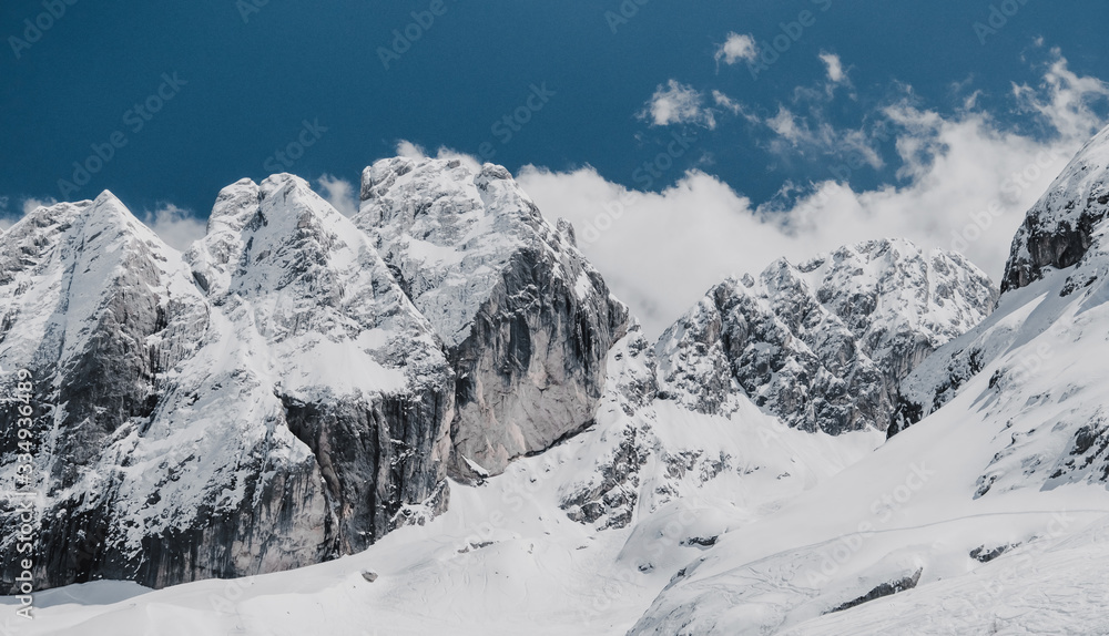 Fototapeta premium Dolomites in Italy. Beautiful landscape of snowy mountains with cloudy sky. Panorama shot of rocks and snow.
