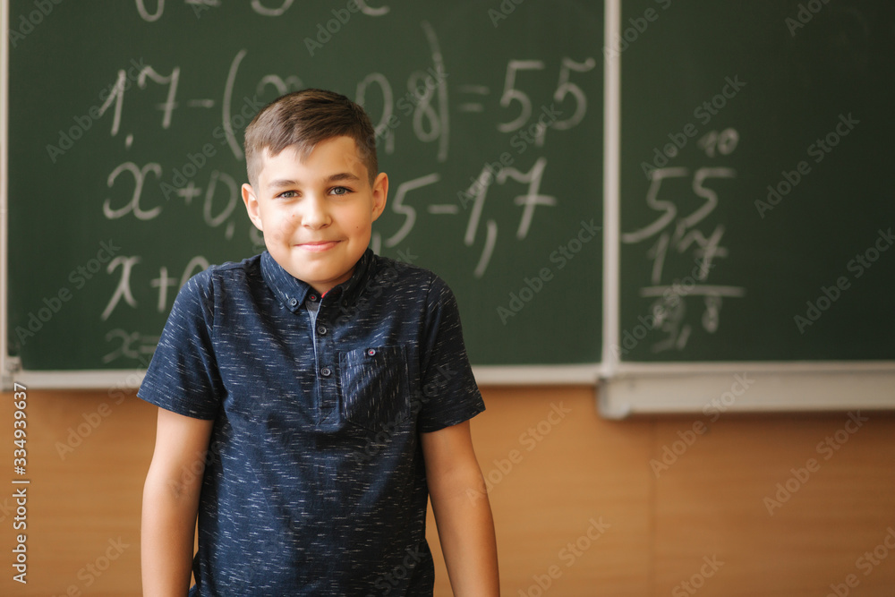 Cute boy stand in the classroom background of blackboard. Education. Elementary school Cute boy stand in the classroom background of blackboard. Education. Elementary school