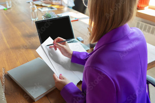 Counting. Young caucasian business-woman working in office, looks stylish. Paperwork, analyzing, looking for desicion. Concept of finance, business, girl power, inclusion, diversity feminism photo