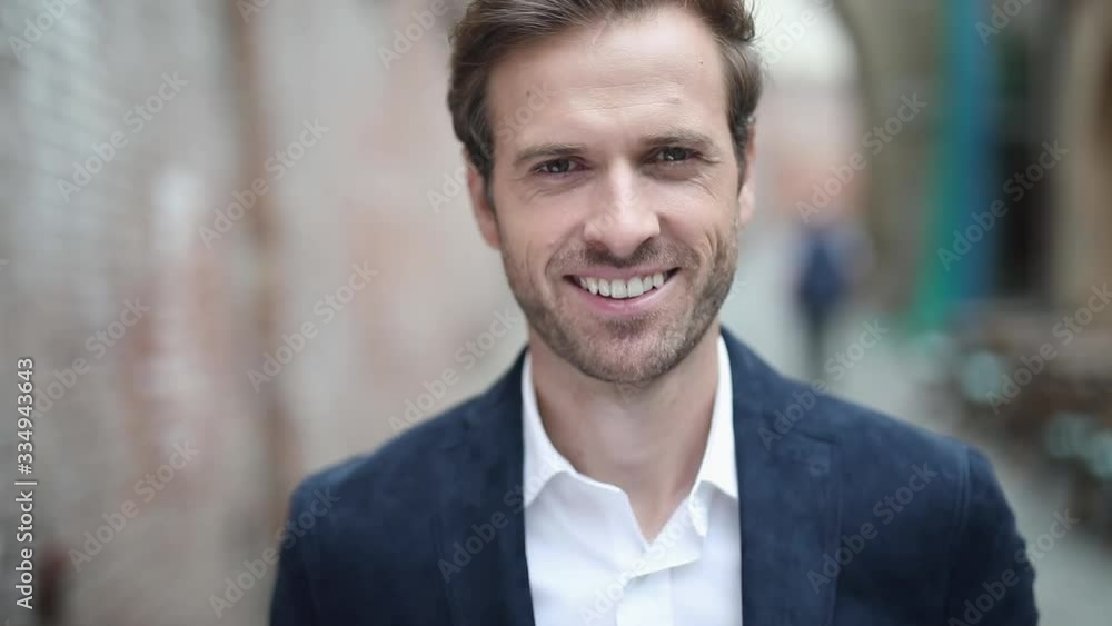 close up of a young sexy businessman wearing a navy suit and looking at camera while smiling wide, outdoor close up of a young sexy businessman wearing a navy suit and looking at camera while smiling wide, outdoor