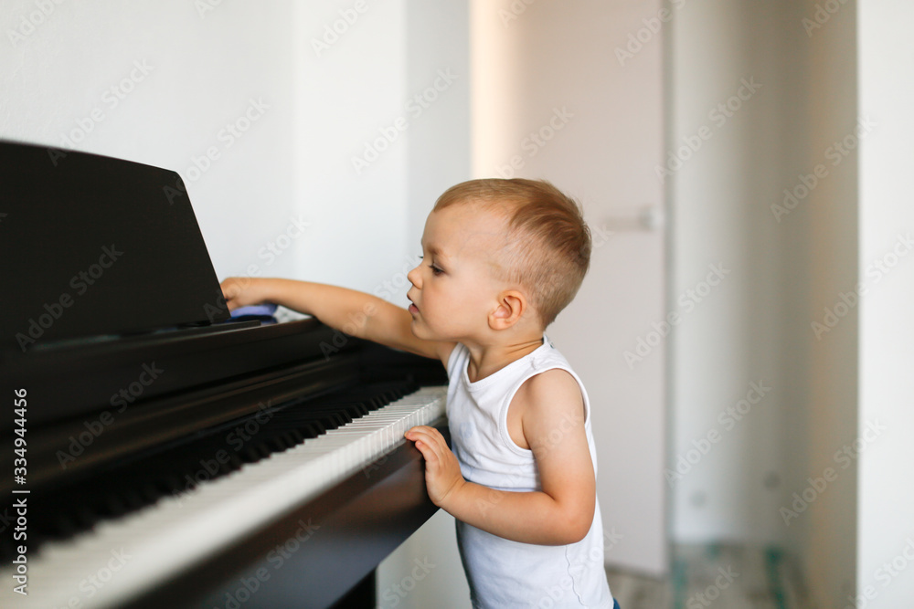 Fototapeta toddler boy wipes the piano, child wipes dust