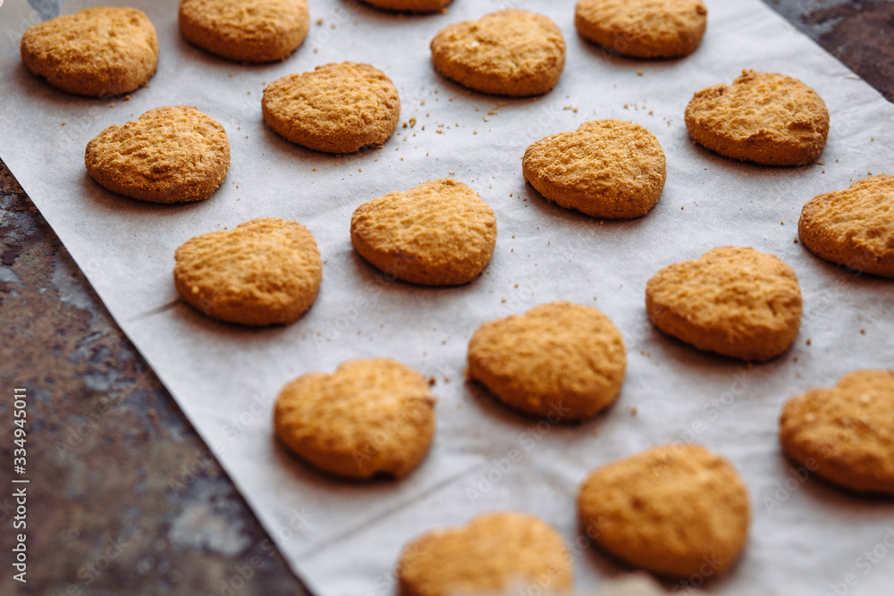 Freshly baked heart-shaped cookies on parchment paper Freshly baked heart-shaped cookies on parchment paper
