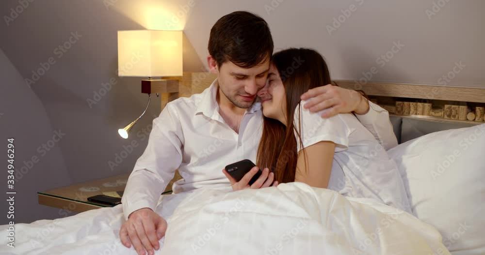 loving spouses are embracing sitting in bed at evening before sleep