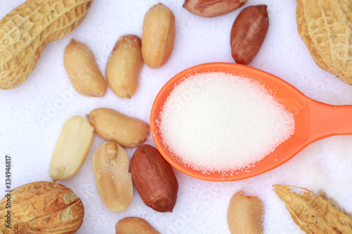 Raw peanut with salt on orange spoon, Focus on red peanut