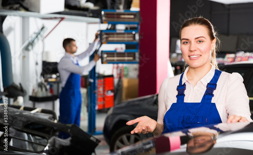 Female mechanic showing car after painting