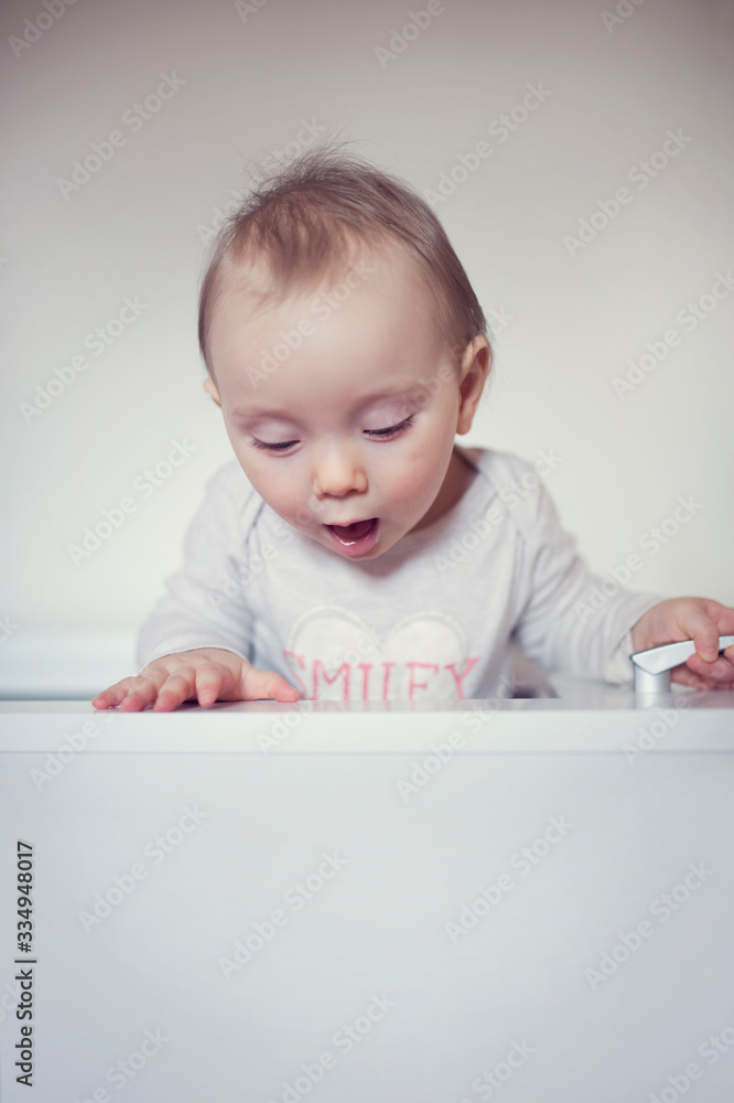 Amazed child looking down behind the wall. Curious baby climbs out. Little funny girl look out. Amazed child looking down behind the wall. Curious baby climbs out. Little funny girl look out.