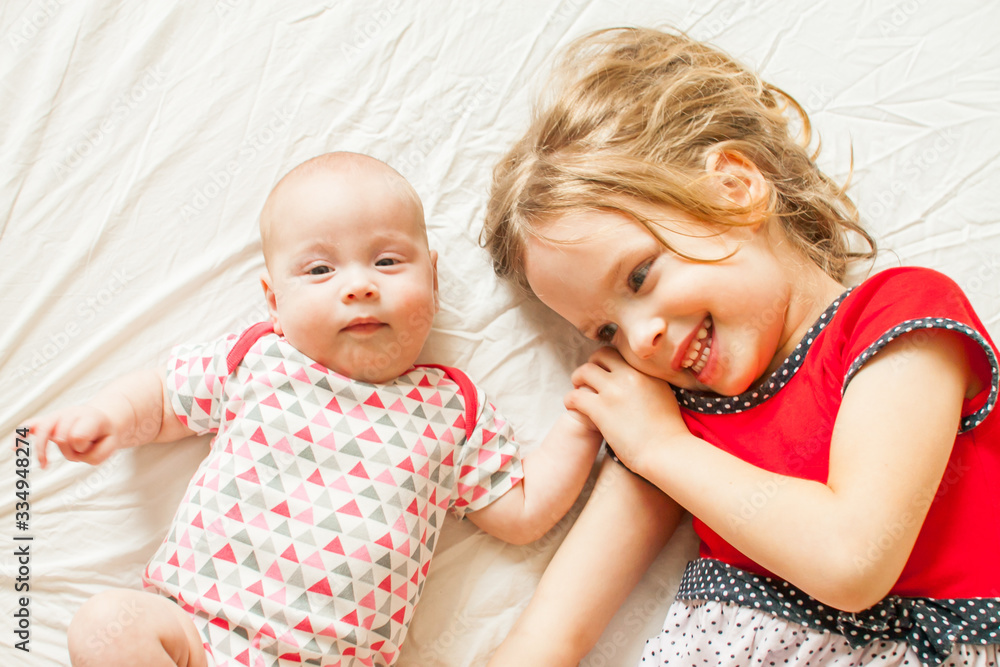 two pretty sisters: the eldest and younger, are lying on the bed two pretty sisters: the eldest and younger, are lying on the bed