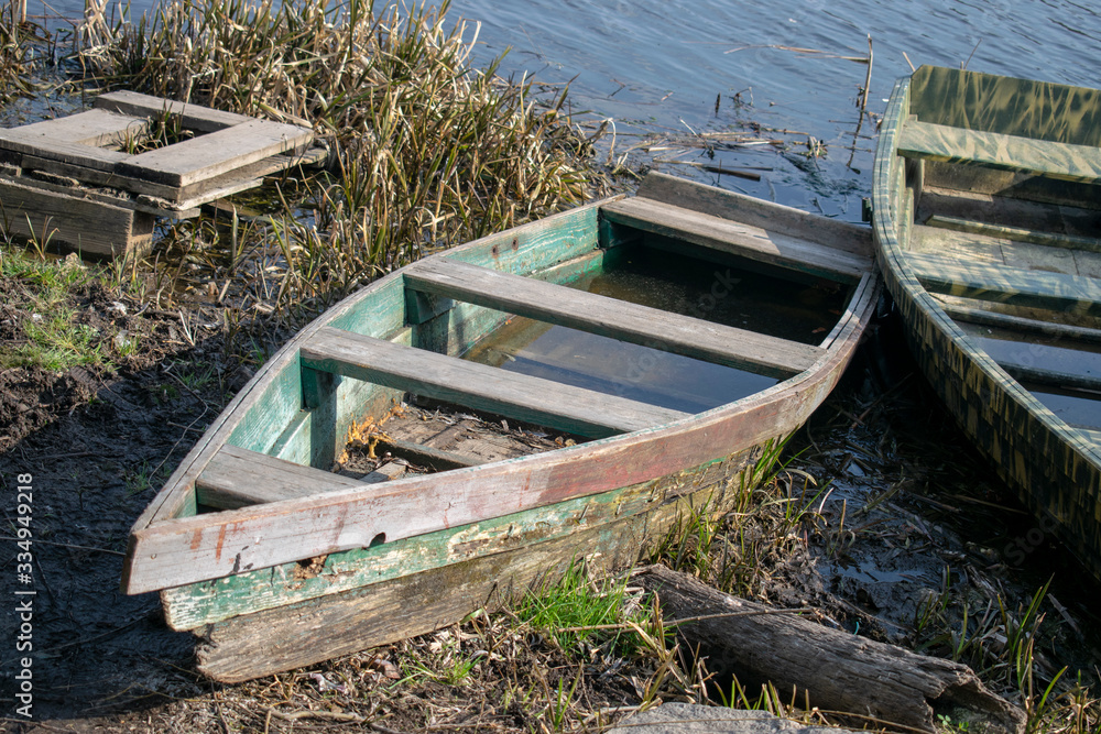 Old broken boat on the river bank with reeds Old broken boat on the river bank with reeds