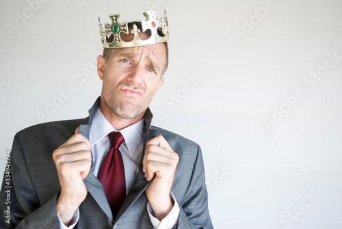 Fotografi Cocky businessman wearing golden jeweled crown popping his collar with an arroga