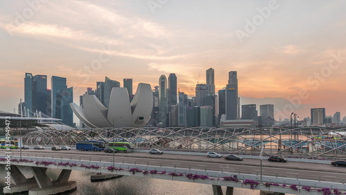 Fototapeta Naklejka Na Ścianę i Meble -  Aerial view over Helix Bridge and Bayfront Avenue with traffic day to night timelapse at Marina Bay, Singapore