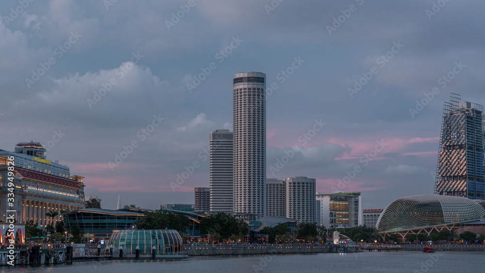 Obraz premium City skyline with skyscrapera and Esplanade Theatres on the Bay in Singapore at dusk, with beautiful reflection in water day to night timelapse