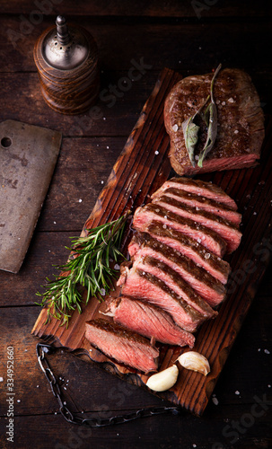 Sliced medium rare grilled beef steak with salt, rosemary and garlic