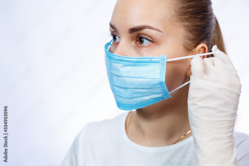 woman health worker demonstrates how to wear a protective medical surgical mask against the virus. Isolated on white background woman health worker demonstrates how to wear a protective medical surgical mask against the virus. Isolated on white background