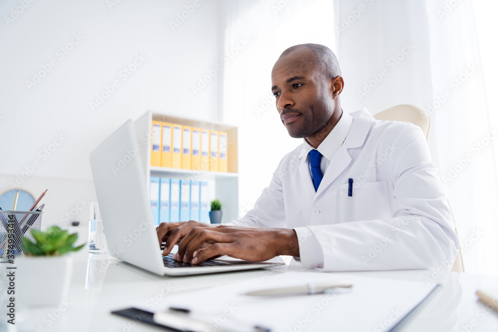 Photo of family doc dark skin guy watch modern technology notebook novelty innovation medical reform cov viral news wear white lab coat sitting chair table office clinic indoors Photo of family doc dark skin guy watch modern technology notebook novelty innovation medical reform cov viral news wear white lab coat sitting chair table office clinic indoors