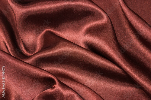 Smooth elegant brown silk or satin luxury cloth texture can be used as abstract background. Crumpled fabric Twisted at the side.