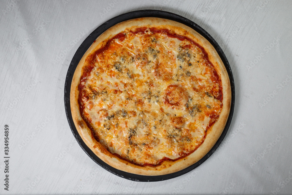 Italian pizza on gray plates on a white plate with spices and seasonings vegetables and meat. Italian pizza on gray plates on a white plate with spices and seasonings vegetables and meat.