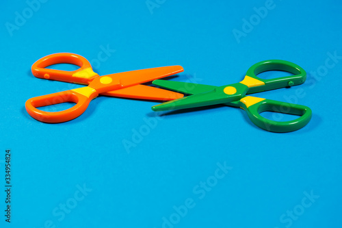 Children's plastic scissors for cutting paper figures on a colored background