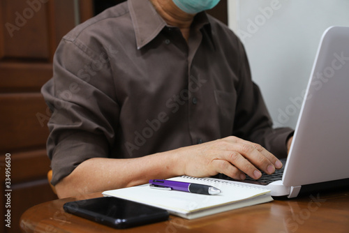 Closeup of man's hand doing his work with notebook computer at home during COVID-19 outbreak around the world. 
