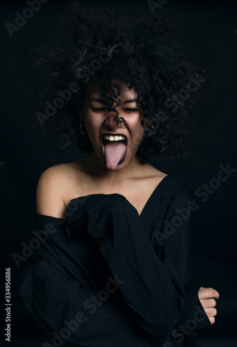Beautiful afro american girl with curly hair posing in studio on dark background.