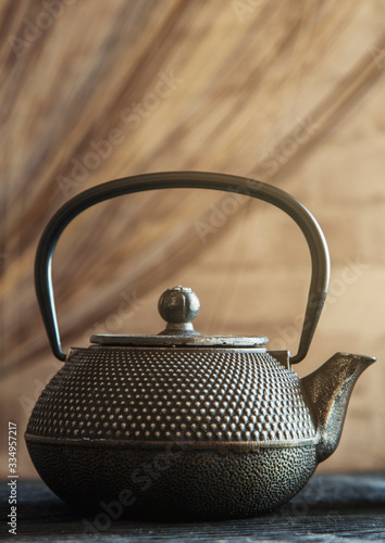 Close up black metall tea pot on a wooden background toning photo