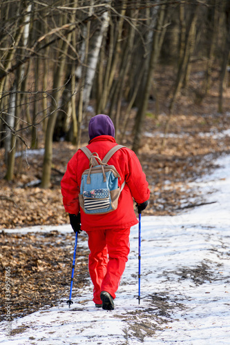 Nordic walking. A woman walking in the woods or Park in winter. Active and healthy lifestyle.
