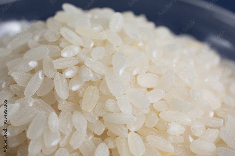 A macro closeup view of a pile of short grain rice in a clear glass bowl. A macro closeup view of a pile of short grain rice in a clear glass bowl.