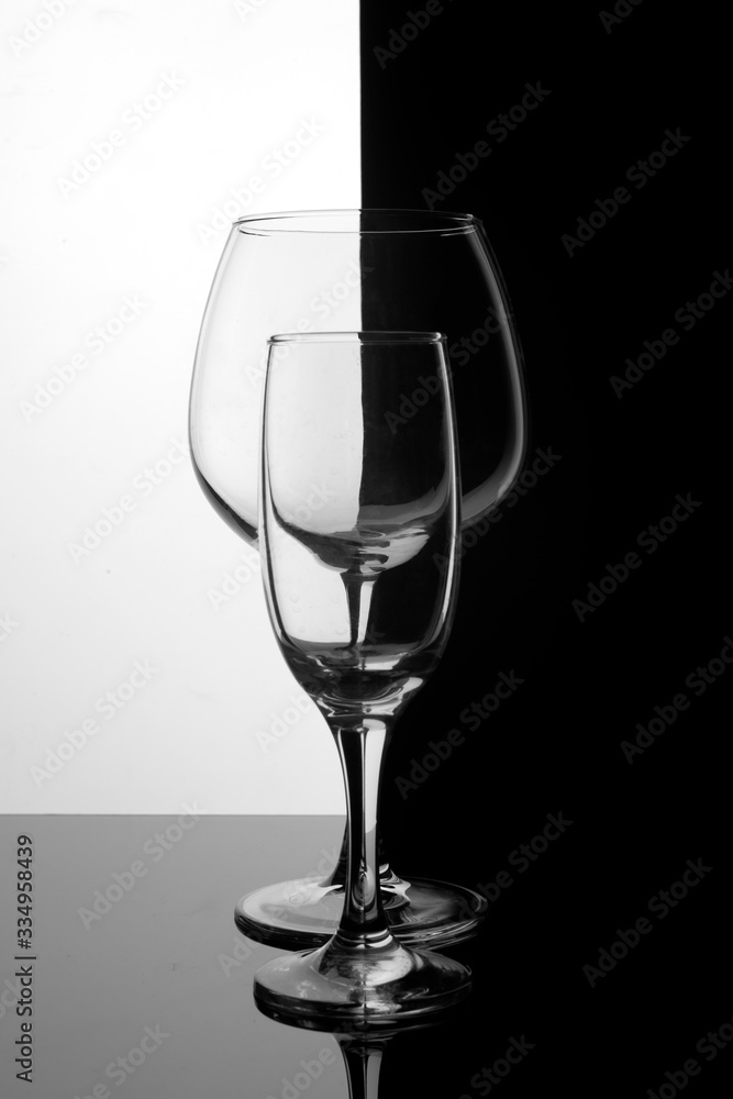 Two glass glasses one behind the other on a black and white background. Geometric symmetry.