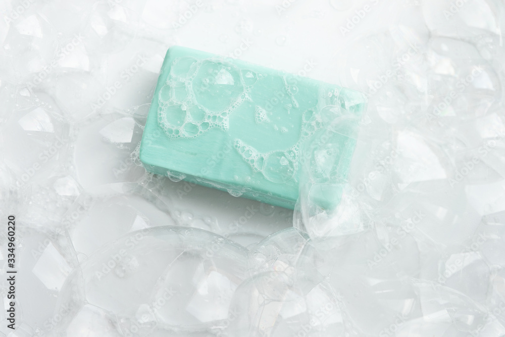 A piece of blue soap in soap bubbles on a white background, top view. A piece of blue soap in soap bubbles on a white background, top view.