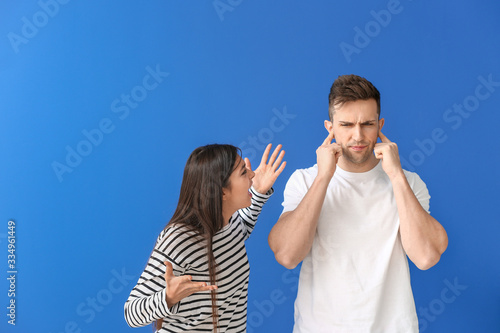 Young couple quarreling on color background