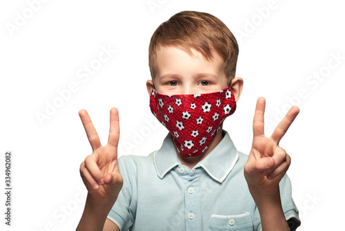 A happy child wearing a protective face mask to prevent virus infection or pollution. COVID-19 struggle and victory concept. Horizontal portrait photo of an young boy, isolated on a white.