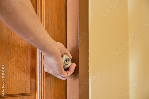 Hand hold the doorknobs of closed wooden door. Health concept to aware for touching the everyday objects.