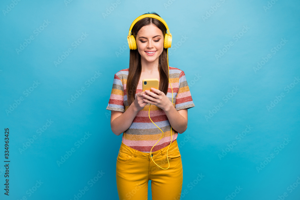 Portrait of her she nice lovely charming cute cheerful cheery girl holding in hand using cell listening radio online isolated over bright vivid shine vibrant blue color background Portrait of her she nice lovely charming cute cheerful cheery girl holding in hand using cell listening radio online isolated over bright vivid shine vibrant blue color background