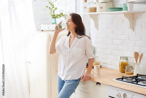Valokuvatapetti Gorgeous woman drinking water in her kitchen