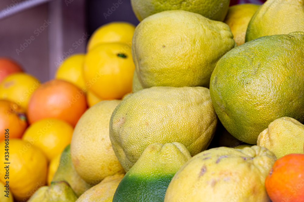 Pile of pomelo fruits at food market, selective focus on foreground on pomelo fruit, blurred citrus fruit on background