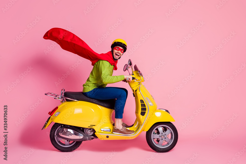 Profile side view of his he nice attractive crazy overjoyed cheerful cheery guy driving moped fast speed wearing cape rescue safe planet isolated over pink pastel color background Profile side view of his he nice attractive crazy overjoyed cheerful cheery guy driving moped fast speed wearing cape rescue safe planet isolated over pink pastel color background