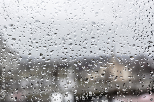 Spring rain. May thunderstorm. Raindrops on the glass. The texture of the drops. Wet window. Chill day. Inclement weather. Torrential rain. View of the world from the window.