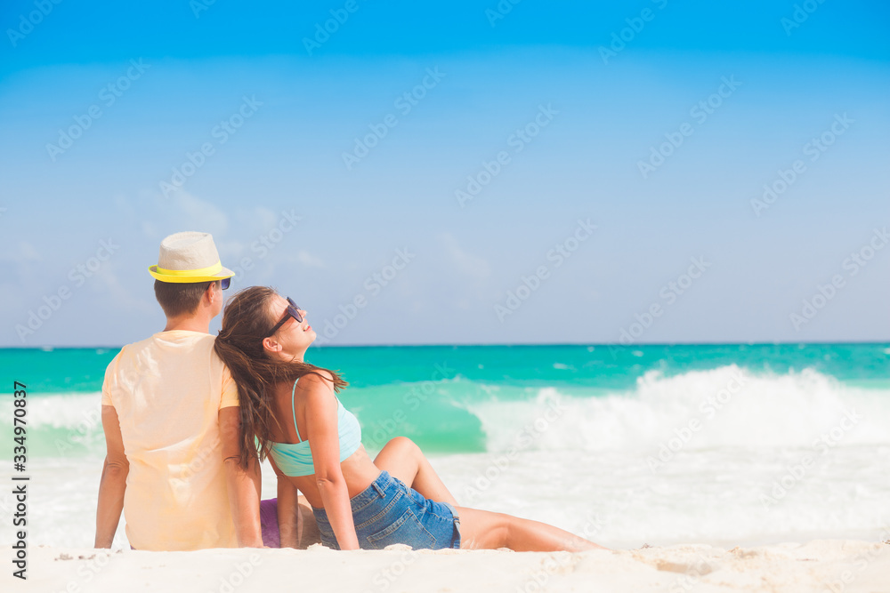 Beach couple sitting on white sand beach on romantic travel honeymoon vacation summer holidays romance. Young happy lovers, Cayo LArgo, Cuba