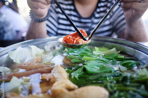 Woman holding sliced beef meat by chopsticks shabu shabu is Korean or Japanese style beef in hot pot dish of thinly sliced meat and vegetables boiled in water. delicious food most popular in thailand. photo